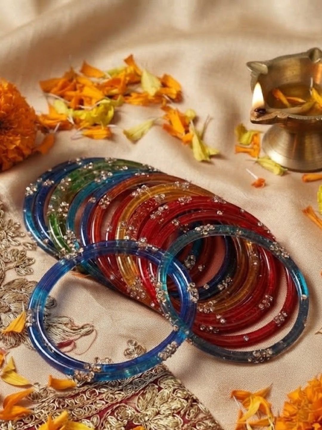 The set laid out on a cream dupatta with marigold petals and a brass diya